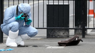 A forensic officer takes photographs of knives on the ground near a backpack after Mr Ali's arrest on Parliament Street, London.