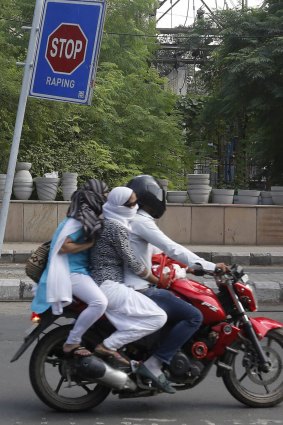 Commuters ride past an anti-rape sign in New Delhi.