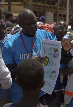 A UNICEF worker with a poster on how to prevent the spread of the Ebola.