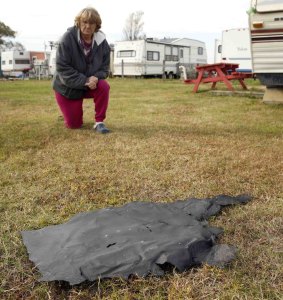 Sandy Saxby kneels next to a piece of rocket debris in Chincoteague, Virginia, near the Wallops Island launch site.