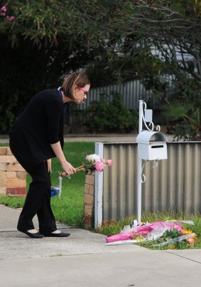 A woman leaves flowers outside the home where a man killed his wife and himself with a high-powered rifle.