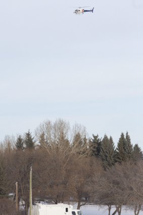 Police use a helicopter to search for the Alberta gunman, who was later found dead.