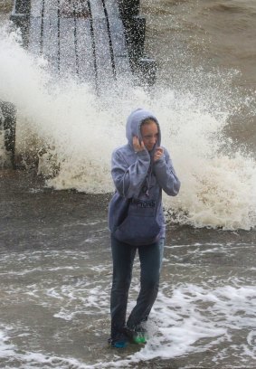 Sylvia Brown, 15, walks through waves as they wash ashore near a pier.