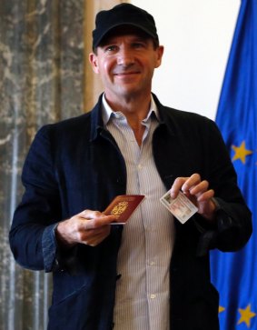 Ralph Fiennes poses for a photograph after receiving his Serbian passport.