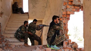 Kurdish People's Protection Units (YPG) fighters take up positions inside a damaged building in al-Vilat al-Homor neighborhood in Hasaka city in July 2015.