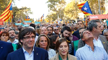 Catalan President Carles Puigdemont, left, takes part in a march to protest against the National Court's decision to imprison civil society leaders.