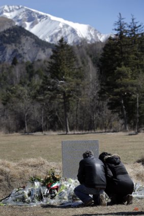Innocent lives lost: Family members of a victim kneel by a stele and flowers laid where the Germanwings jetliner crashed.
