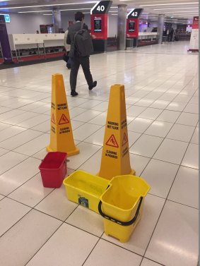 Buckets collect water under a leaky roof at Virgin Terminal 2, while flights are delayed due to rain and lightning.