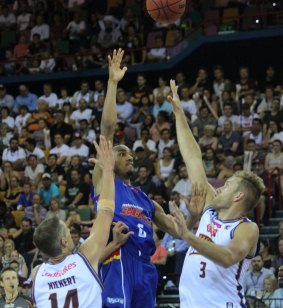 Terrance Ferguson floats a shot attempt over the defence of Brisbane forwards Daniel Kickert and Mitch Young.