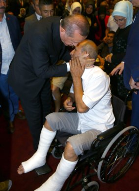 Mr Erdogan hugs a wounded civilian during the commemorative event in Ankara.