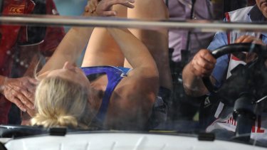 Sally Pearson holds her wrist as she is carried awa.