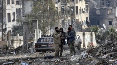 Syrian troops and pro-government gunmen stand in the Ansari neighbourhood, east Aleppo.