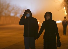Moves to fight pollution: People walk wearing masks on a heavy pollution evening in Beijing.