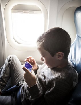 Boy (8yrs) using smartphone on airplane