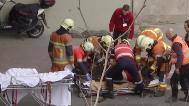 Emergency rescue workers stretcher a person at the site of an explosion at a metro station in Brussels.