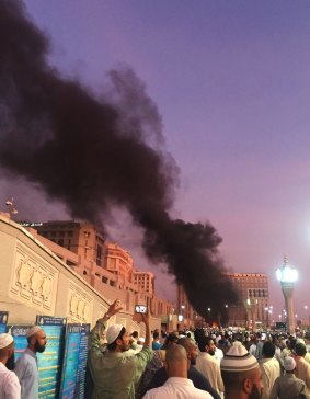 People stand by an explosion site in Medina, Saudi Arabia.