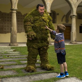 A moss man plays with his child as he gets ready to take part during the Corpus Christi procession in the small village of Bejar, Spain.