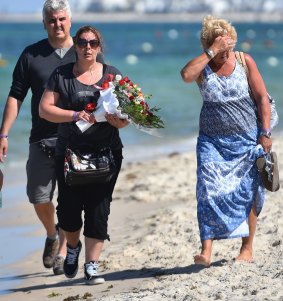 Shocked holidaymakers carry a bouquet of flowers to lay at the scene of the Tunisian resort attack. 
