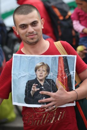 A migrant from Syria holds a picture of German Chancellor Angela Merkel.