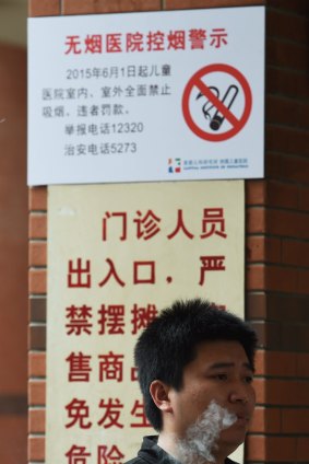 A man smokes a cigarette near the entrance to a children's hospital in Beijing on June 1. Many fear the new laws will be poorly enforced.