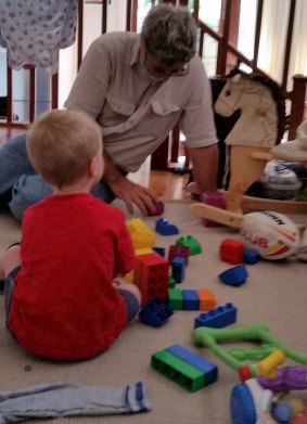 Mike playing with his grandson; he would do it for love, but appreciates the money the Registered Care Provider scheme brings in.