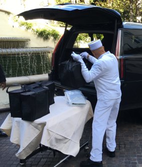 A Peninsula Hotel bellboy loads picnic hampers into the Cadillac.