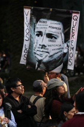 Demonstrators in Mexico City hold a picture of President Enrique Pena Nieto bearing the slogan "we want them alive".