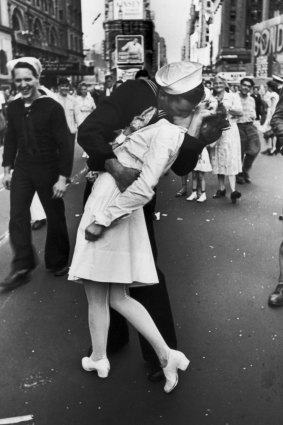 A jubilant American sailor clutching a white-uniformed nurse in a back-bending, passionate kiss as he vents his joy while thousands jam Times Square to celebrate the long awaited-victory over Japan. 