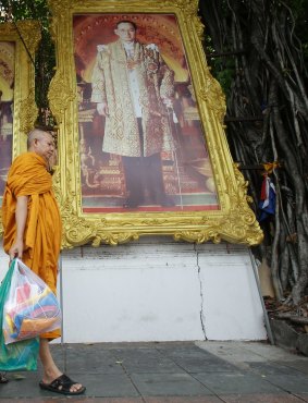 A Buddhist monk walks past a portrait of King Bhumibol Adulyadej in Bangkok.