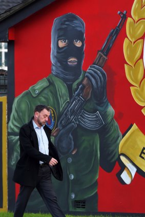Historical burden: A man walks past a loyalist paramilitary mural on the Newtownards road in Belfast. The trigger for the latest crisis came from claims of continued paramilitary activity by the IRA.
