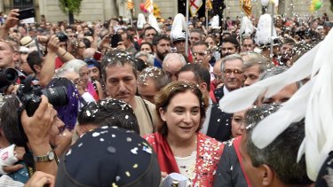 People throw confetti as Ada Colau (in red) crosses Sant Jaume Square after being sworn in as mayor of Barcelona.