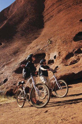 Cyclists look up to Uluru's heights.