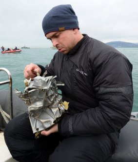 A Russian Emergency Ministry diver inspects a piece of the plane recovered from the sea. 