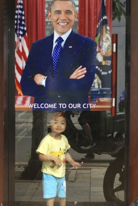 A young girl smiles under a poster of US President Barack Obama in Hanoi, Vietnam.