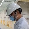 A worker collects a sample of paint for quality control at the Nippon Paint plant in Qingyuan,China.