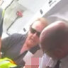 A still from passenger Daniel Defina’s footage of the teenager being restrained by a Jetstar employee, Barry Clark and the pilot.