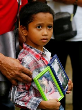Adrian Perigrino holds portraits of his parents, both victims of extra-judicial killing, in suburban Paranaque city south of Manila in March.
