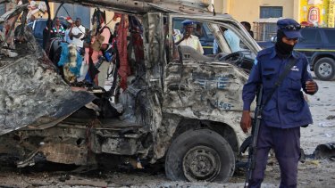 Security forces stand near the wreckage of a minibus at the scene of a car bomb attack in Mogadishu last month.