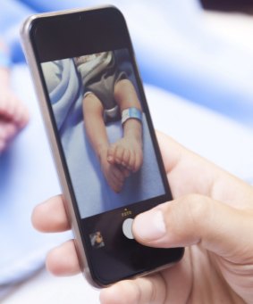 Hands taking newborn baby photo with smartphone. Photo taken in hospital.  iStock Image