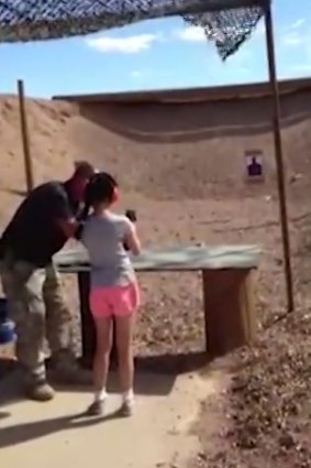 Shooting instructor Charles Vacca stands next to the 9-year-old girl at the Last Stop shooting range at Bullets and Burgers in White Hills, Arizona.