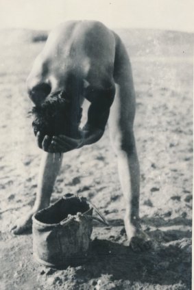 A member of the 7th Australian Light Horse Regiment having a bath from a canvas bag in the desert.