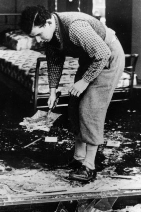 A worker clearing broken glass of a Jewish shop following the anti-Jewish riots of Kristallnacht in Berlin in 1938.  