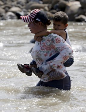 Carrying a child across the Tachira
 River this week as the presidents of Venezuela and Colombia spar. 