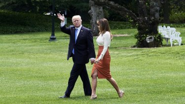 US President Donald Trump waves while walking towards Marine One with wife Melania Trump.