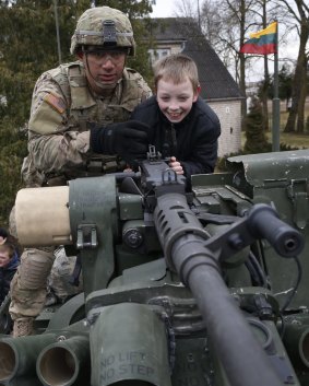 A member of the US Army's 2nd Cavalry Regiment shows a gun to a young boy on a Stryker vehicle during the ''Dragoon Ride'' in Salociai.
