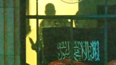 Gunman Man Haron Monis seen through a window of the Lindt cafe.