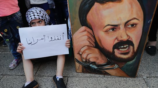 A Palestinian child holds a placard in support of "our prisoners" next to a painting of Marwan Barghouti in the Lebanese capital, Beirut.