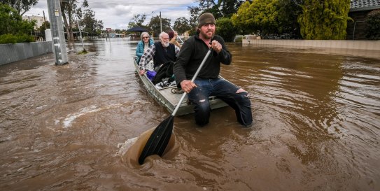 Tom Collins and mate Tim Tyler rescue Max and Julia Hastilow from floodwaters that have devastated the town of Rochester in central Victoria. 