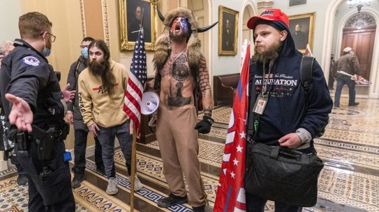 FILE - In this Wednesday, Jan. 6, 2021 file photo, supporters of President Donald Trump, including Jacob Chansley, center with fur and horned hat, are confronted by Capitol Police officers outside the Senate Chamber inside the Capitol in Washington. A video showed Chansley leading others in a prayer inside the Senate chamber. (AP Photo/Manuel Balce Ceneta)