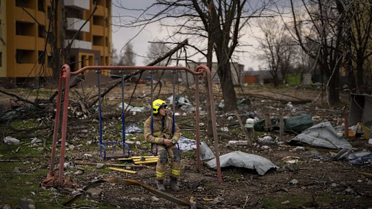 A firefighter sits on a swing next to a building destroyed by a Russian bomb in Chernihiv on Friday, April 22, 2022. (AP Photo/Emilio Morenatti)